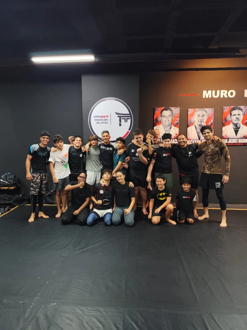 Alumnos y profesores de OPENMAT posando juntos junto al logo del equipo